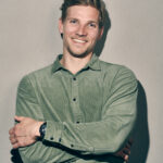 Een jonge man in een groen shirt poseert voor een foto en laat zijn identiteit zien.